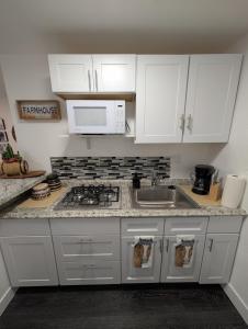 a white kitchen with white cabinets and a sink at Rancho Las Casitas in Tucson +10 photos