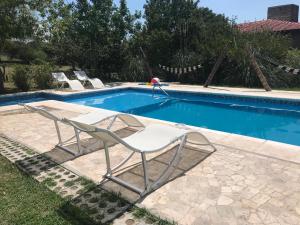 a pair of chairs sitting next to a swimming pool at Cabañas LAS GEMELAS in Bialet Massé