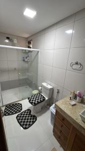 a bathroom with a shower and a toilet with black and white mats at Casa centro in Porto Seguro