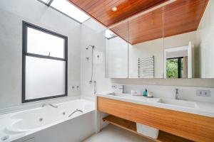 a bathroom with a tub and a sink and a mirror at Casa Atalaia 550m Praia c/ Hidro by Achei Camboriú in Praia Brava +58 photos