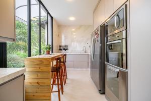 a kitchen with stainless steel appliances and a bar with stools at Casa Atalaia 550m Praia c/ Hidro by Achei Camboriú in Praia Brava