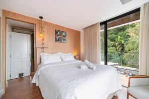a bedroom with a white bed and a large window at Casa Atalaia 550m Praia c/ Hidro by Achei Camboriú in Praia Brava
