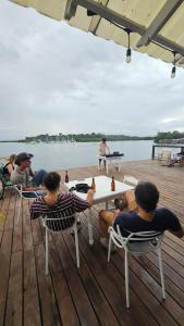a group of people sitting around a table on a dock at Hostal Blue Olas in Carenero +12 photos