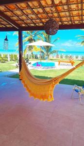 a hammock on a beach with the ocean in the background at Casa Beira Mar - Praia de Aver o mar - Sirinhaém in Sirinhaém