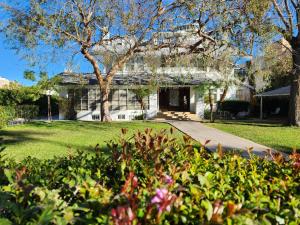 a white house with a tree and some bushes at Orange Drive Hostel in Los Angeles