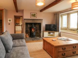 un salon avec un canapé et une cheminée dans l'établissement Stone & Fleece Cottage, à Holmebridge