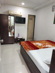 a bedroom with a bed and a tv on the wall at Hotel Dream in Rajkot +2 photos