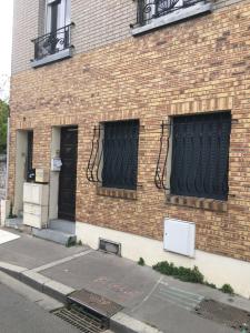 ein Backsteingebäude mit zwei Fenstern mit schwarzen Toren in der Unterkunft Studio 20m2 Ground Floor street in Colombes