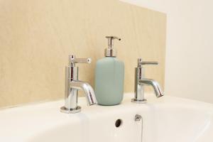 a bottle of soap sitting on a sink with two faucets at Spacious 6-Bed Home for Work Crews & Groups in Sketty +114 photos