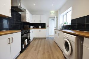 a kitchen with white cabinets and a washer and dryer at Spacious 6-Bed Home for Work Crews & Groups in Sketty