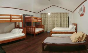 a room with four bunk beds and wooden floors at Villa Bella 3 Beach Resort in Buyog