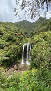 ein Wasserfall inmitten eines üppig grünen Tals in der Unterkunft Freestyle House Hostel in Lligua