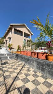 a building with a lot of potted plants in front of it at BFMS Villa, Royal Purandar in Purandhar