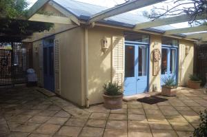 une maison avec une porte bleue et une terrasse dans l'établissement Athelney Cottage Bed and Breakfast, à Adélaïde