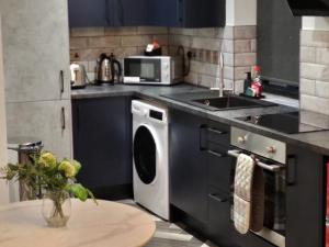 a kitchen with a washing machine and a sink at Affordable Serviced Apartment Perfect for Contractors in PE1 Short & Long Term Stays - Free WIFI - Free Parking - With Sofa Bed - Full Kitchen in Peterborough +14 photos