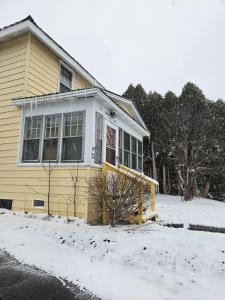 una casa amarilla con nieve delante en NiceShortStayMassena, en Massena