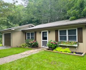 a house with flowers in the front yard at Cozy Creek Cottages in Maggie Valley
