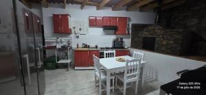 a kitchen with red cabinets and a white table and chairs at Guesthouse Los Geranios in Mocanal