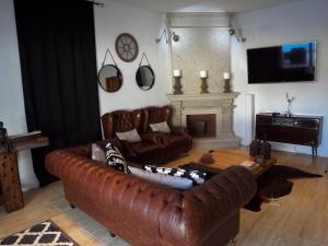a living room with a leather couch and a fireplace at DH Country House in Évora