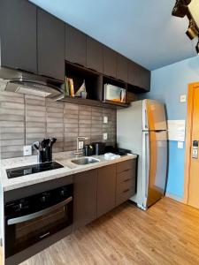 a kitchen with a sink and a refrigerator at LIV apto 1211 - Loft novo com vista in Porto Alegre