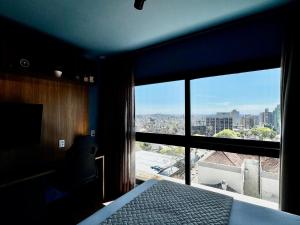 a bedroom with a bed and a large window at LIV apto 1211 - Loft novo com vista in Porto Alegre +13 photos
