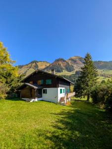 ein Haus auf einem Feld mit Bergen im Hintergrund in der Unterkunft Appt dans chalet en pleine nature aux Mosses in Les Mosses