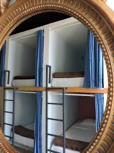 Capsule Hostel في مدينة ميكسيكو: مرآة تعكس سريرين بطابقين مع ستائر زرقاء