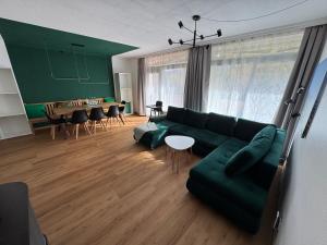 een woonkamer met een groene bank en een tafel bij Bergtraum Schwimmbad, Sauna, Familienbett, Kinderbett, 2 Bäder in Bad Harzburg