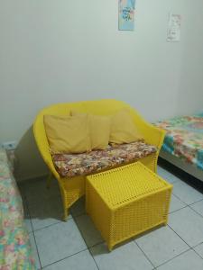 ein gelber Korbstuhl mit Kissen und einer Bank in der Unterkunft Hostel da Josi - Porto de Galinhas in Porto De Galinhas