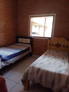 two beds in a room with a window at Sitio Recanto das águas in São João del Rei