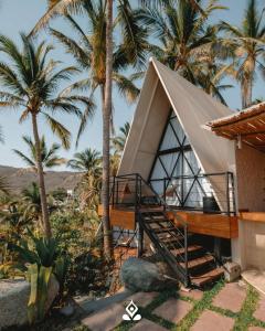 a house with a triangular roof with palm trees at Shambhala Holistic Resort Only Adults in Manzanillo