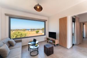 a living room with a couch and a large window at Lotus Luxury Apartments in Kremasti
