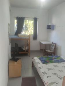 a bedroom with a bed and a desk and a window at Xixova hostel in São Vicente