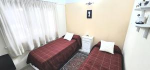 two beds sitting in a room with a window at Departamento de 2 Dormitorios con Cochera Cubierta WIFI Aire Acondicionado está bien Céntrico y a Metros del Mar in San Bernardo