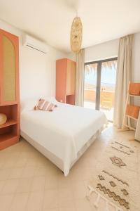 Un dormitorio con una cama blanca y una ventana grande. en Dar Oumnass, charme authentique tout confort !, en Oumnas