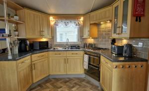 a kitchen with wooden cabinets and a sink and a stove at MOLLIES DEN 6 Berth 2 Bedrooms Waterside Leisure Park Ingoldmells in Ingoldmells