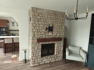 a stone fireplace in a living room with a chair at Gödöllő Country Home in Gödöllő