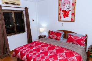 a bedroom with a red bed and a window at LUXOR GARDEN, Free Pool & Gym, 10mins from Airport, 24-7 Security, Backup Power in Accra