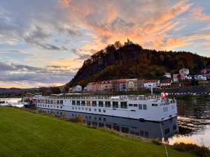 un bateau de croisière amarré sur une rivière avec une colline dans l'établissement Podzámčí - útulný byt na nábřeží pod zámkem, à Děčín