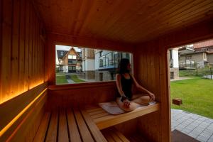 a woman sitting on a bench in a sauna at Cyrhla Apartamenty - sauna, playroom, free parking & wifi in Zakopane