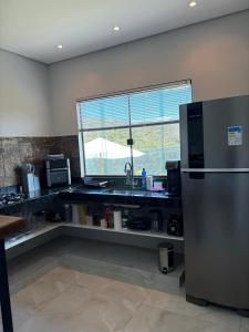 a kitchen with a stainless steel refrigerator and a window at Cipó Lofts - Serra do Cipó in Santana do Riacho