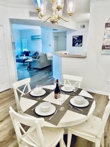 een eettafel met witte stoelen en een fles wijn bij Coastal Condo with pool, minutes from beach in Saint Simons Island