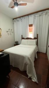 a bedroom with a white bed and a window at HOTEL FAZENDA ARIZONA -proximo peruaçu in Januária