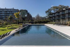 a swimming pool with chairs and a building at Monoambiente a 5 minutos del aeropuerto ESPECTACULAR in Montevideo