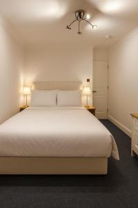 a bedroom with a large white bed with two lamps at Wood Green Central Cozy Rooms in London