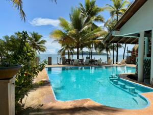 a swimming pool with palm trees and the ocean at Cabañas Time Out in Santa Catalina +28 photos