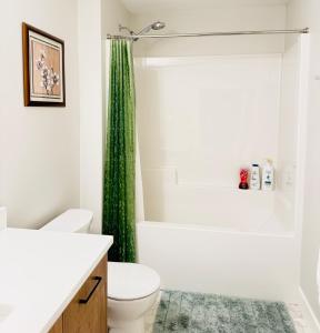 a bathroom with a toilet and a green shower curtain at Casa Del Mar-A family Suite in Victoria in Langford +35 photos