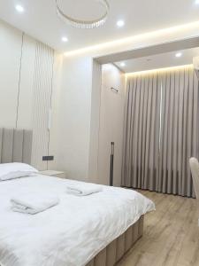 a bedroom with a large white bed and a chandelier at Уютная двух комнатная квартира возле Simketsity mall in Shymkent