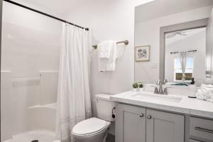 a white bathroom with a toilet and a sink at Ultimate Steps to Beach Hot Tub Family Fun in Bolivar Peninsula +16 photos