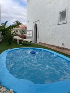 a blue swimming pool in front of a house at Apartamento con jardín y pequeña piscina privada para refrescarse in Maspalomas